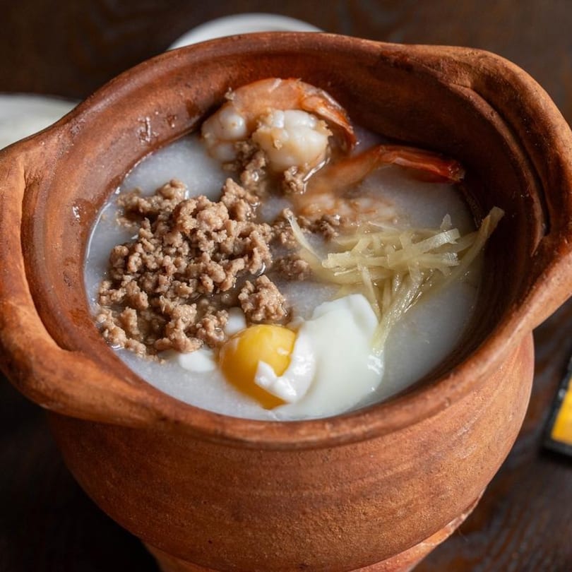 Clay pot of congee with minced pork, shrimp, ginger, and a poached egg.