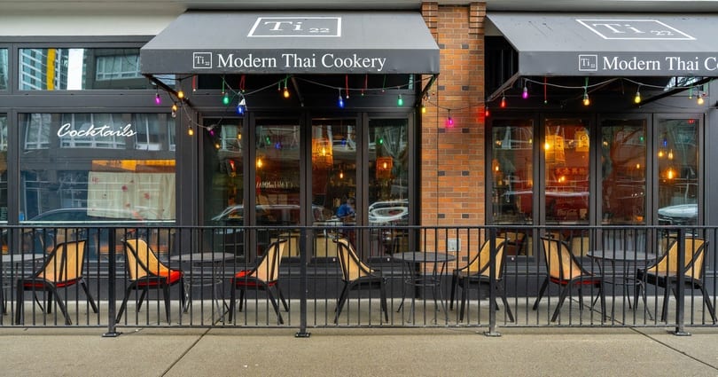 Ti 22 Modern Thai Cookery storefront with outdoor seating, black awnings, and colorful string lights.
